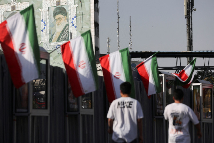 People walk near a mural of Iran's Supreme Leader Ayatollah Ali Khamenei amid the Iran-Israel conflict in Tehran on June 23, 2025.