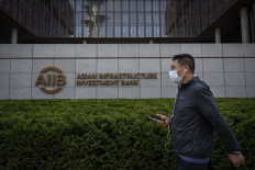 A man walks past the logo of the Asian Infrastructure Investment Bank (AIIB) at the headquarters in Beijing on June 15, 2023. 