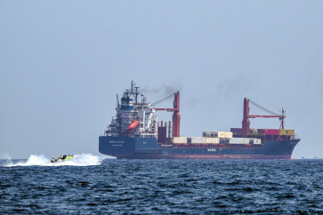 A boat approaches the St Kitt's and Nevis-flagged container ship Marsa Victory while cruising in the waters of the Strait of Hormuz off the coast of Khasab in Oman's northern Musandam peninsula on June 25, 2025. 