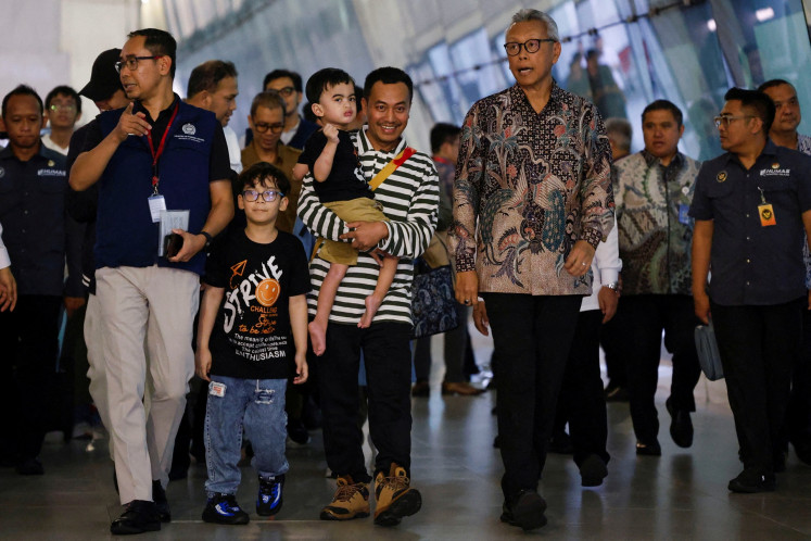 Ali Murtado (center), 20, carries his son on June 24, 2025 as he walks with the Foreign Ministry's director general for protocol and consular affairs, Andy Rachmianto (right), and citizen protection director Judha Nugraha (left) after they were evacuated from Iran and arrived at Soekarno-Hatta International Airport in Tangerang, Banten, after United States President Donald Trump announced a ceasefire between Israel and Iran.