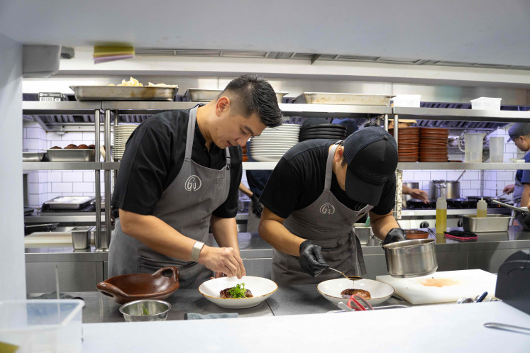 Chef Arnold plates one of the main dishes, adding final touches alongside Glou’s in-house team.