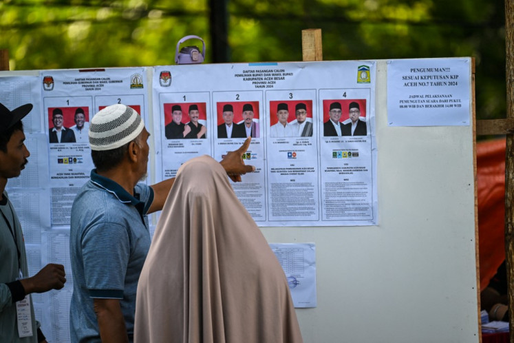 Exercising their right: People check candidates on Nov. 27, 2024, before casting their ballots during the 2024 regional head elections in Banda Aceh, Aceh. That day, Indonesians voted to elect local leaders in the country's biggest simultaneous regional election.