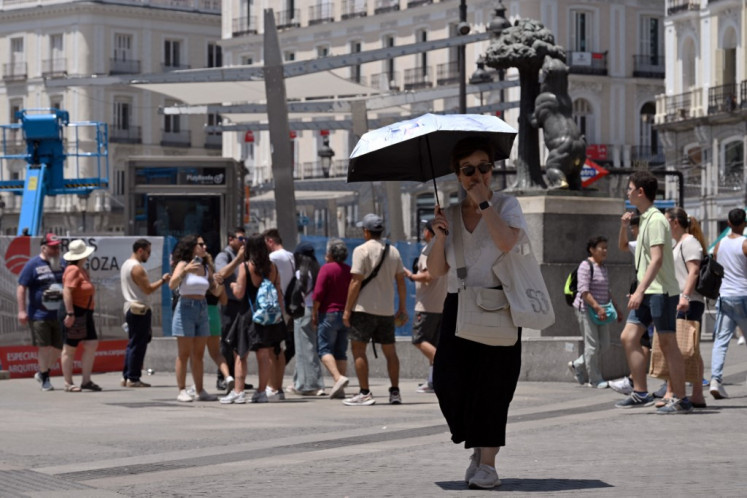 A person uses an umbrella as protection from the sun at Puerta del Sol square in Madrid, on June 18, 2025, as a heatwave hits Spain. 