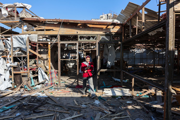 A Palestinian woman walks on debris at Al-Baqa cafeteria which was devastated in an Israeli strike on the Gaza City seafront on June 30, 2025. 