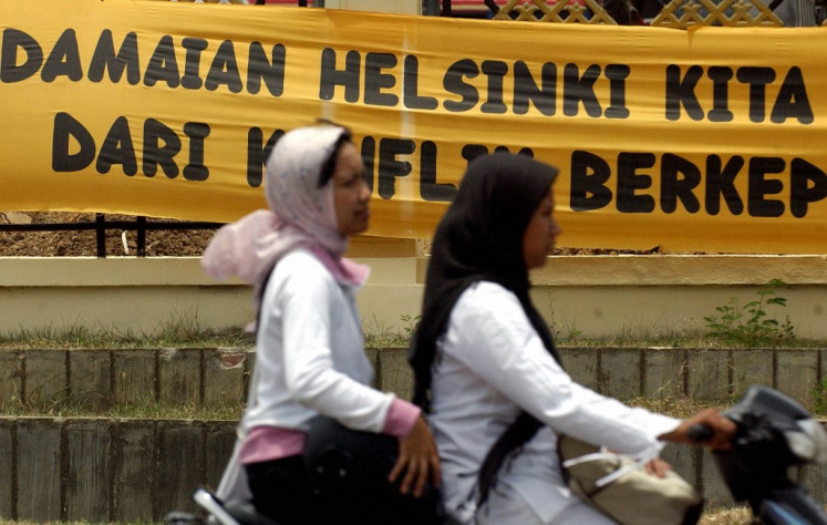 War and peace: Acehnese motorists pass a banner promoting peace on Sept. 14, 2005, in Banda Aceh, Aceh. Under a long-elusive peace deal between Jakarta and the Free Aceh Movement (GAM), observers from the European Union and Association of Southeast Asian Nations monitored the first phase of GAM's disarmament and the pullout of government forces.
