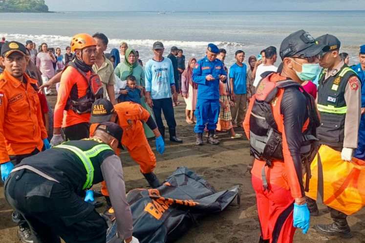 This handout photo taken and released on July 3, 2025 by the National Search and Rescue Agency (BASARNAS) shows a rescue team moving a victim's body brought to shore earlier by local fishermen after a ferry sank on its way to Bali, in Banyuwangi, East Java. 