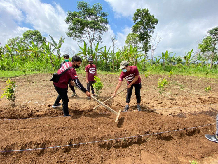 Members of Cool Young Farmers (Petani Muda Keren) community based in Bali planting a tree on agricultural land in this undated photo.