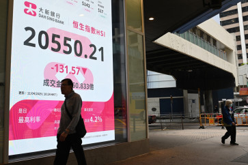 Pedestrians walk in front of an electronic board showing the opening numbers on the Hang Seng Index in Hong Kong on April 11, 2025.