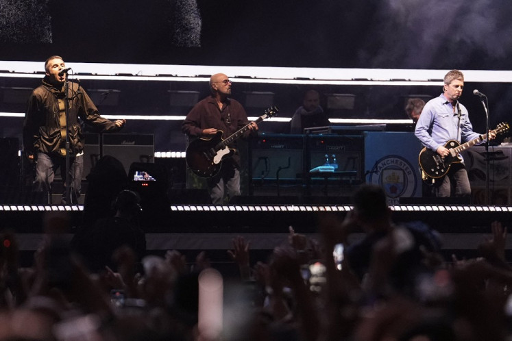 (Left-right) Liam Gallagher, lead singer, Paul Arthurs, guitarist and Noel Gallagher, singer and guitarist of British rock band Oasis perform on stage at the Principality Stadium in Cardiff on July 4, 2025, during the opening concert of their highly anticipated reunion tour nearly 16 years after last performing together. 