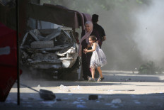 A Palestinian mother and her daughter rush for cover during an Israeli airstrike on the Al-Bureij refugee camp in the central Gaza Strip on July 4.