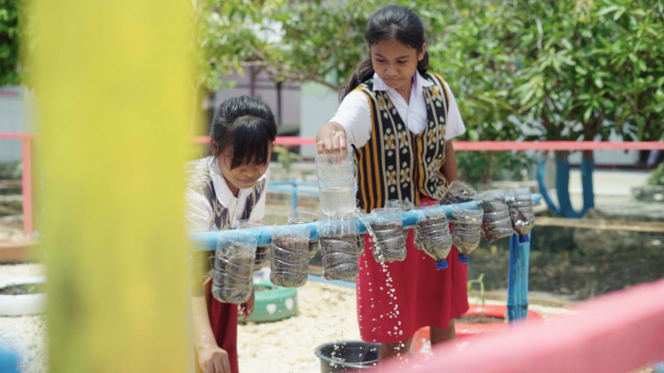 Students from SDN Papela state elementary school in Rote Ndao regency, East Nusa Tenggara, water plastic bottles turned into pots to cultivate vegetables in this undated handout photo. The school was named the AIA 2025 Healthiest School Competition winner for its waste recycling and literacy initative, called Ecolitera.