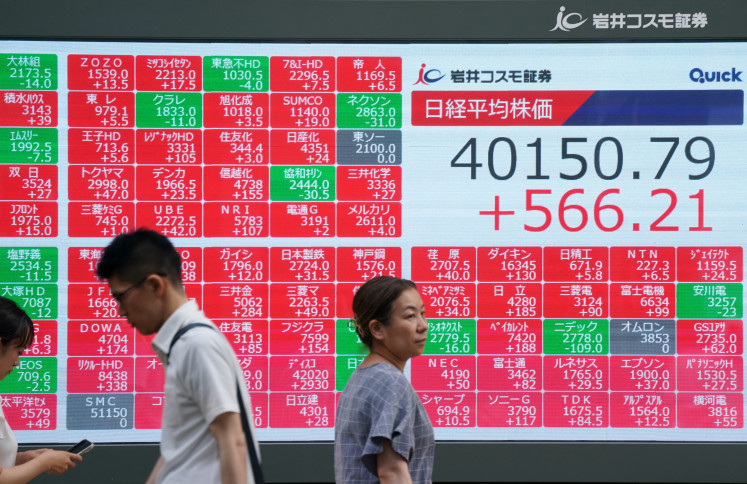 Pedestrians walk in front of an electronic quotation board displaying the Nikkei Stock Average closing price at 40,000 yen level on the Tokyo Stock Exchange in Tokyo on June 27, 2025.