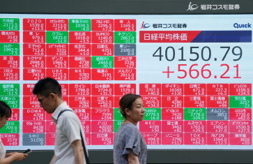Pedestrians walk in front of an electronic quotation board displaying the Nikkei Stock Average closing price at 40,000 yen level on the Tokyo Stock Exchange in Tokyo on June 27, 2025.