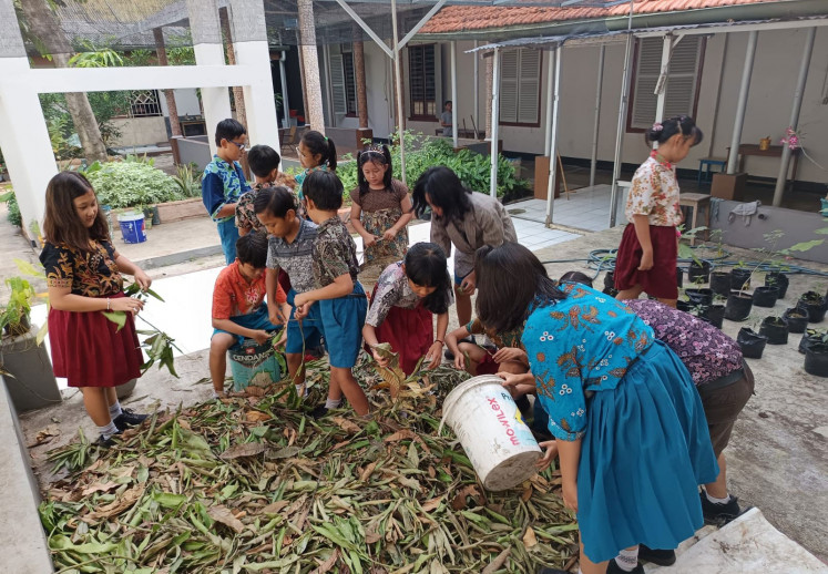 SD Marsudirini Gedangan pupils collect and sort leaf litter to turn into compost.