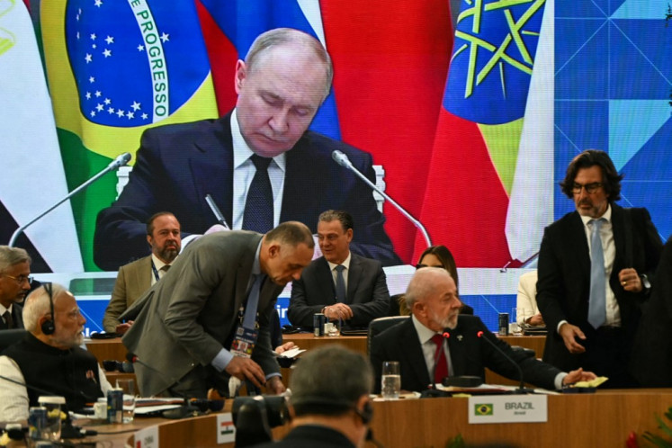 Russia's President Vladimir Putin is seen projected on a screen during the first plenary session of the BRICS summit in Rio de Janeiro, Brazil, on July 6, 2025. 