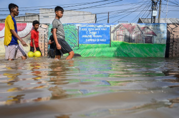 Residents walk through floodwater in South Tangerang, Banten, on July 8, 2025. Heavy rainfall on Monday triggered flooding in several parts of Jakarta and its surrounding areas, including South Tangerang.