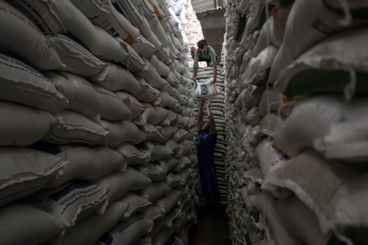 Workers carry rice sacks at the State Logistics Agency (Bulog) warehouse in Cimahi, West Java, on July 10.