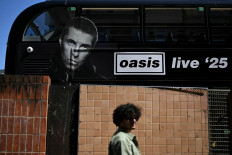 A person walks past an Oasis themed bus in Manchester, northern England on July 11, 2025, ahead of the British rock band's highly-anticipated second leg of their reunion tour. The return of the prodigal Oasis brothers to Manchester Friday, on the second leg of their highly-anticipated reunion tour, has rekindled memories of the city's time as a cultural epicenter.