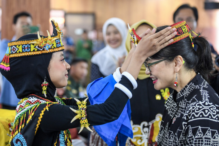 Second Deputy Higher Education, Science and Technology Minister Stella Christie (right) receives a traditional Dayak headband from a student on June 18 during a visit to the Garuda Transformation School at SMAN 10 in Samarinda, East Kalimantan.