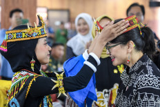 A student presents Deputy Higher Education, Science and Technology Minister Stella Christie (right) with a traditional Dayak headband on June 18, 2025, at a visit to SMAN 10 Samarinda senior high school in the East Kalimantan capital, which has been designated Garuda Transformation School.