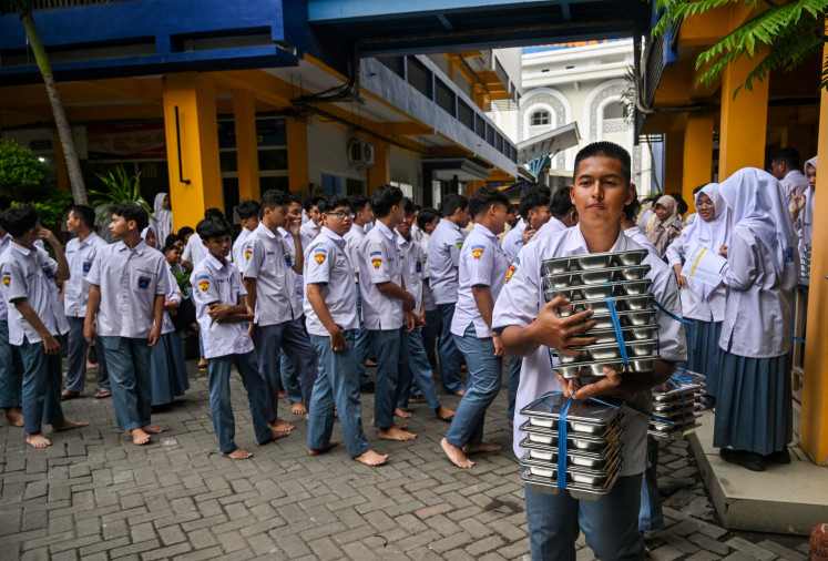 A student carries lunch boxes on the first day of a free meal program at a Muhammadiyah high school in Sidoarjo, East Java, on January 6.