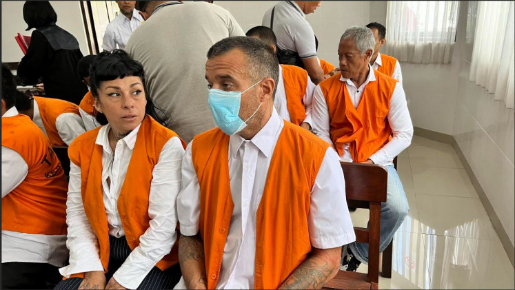 Codefendants Eleonora Gracia (left, front) of Argentina and Elliot James Shaw of Britain wait to be called in for a hearing on July 10, 2025, in their drug trafficking trial at the Denpasar District Court.