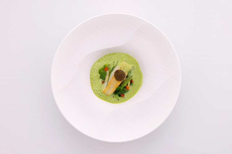 A seared scallop sits atop asparagus, lettuce and pork pancetta—one of the main entrees of The Crown’s tasting menu.