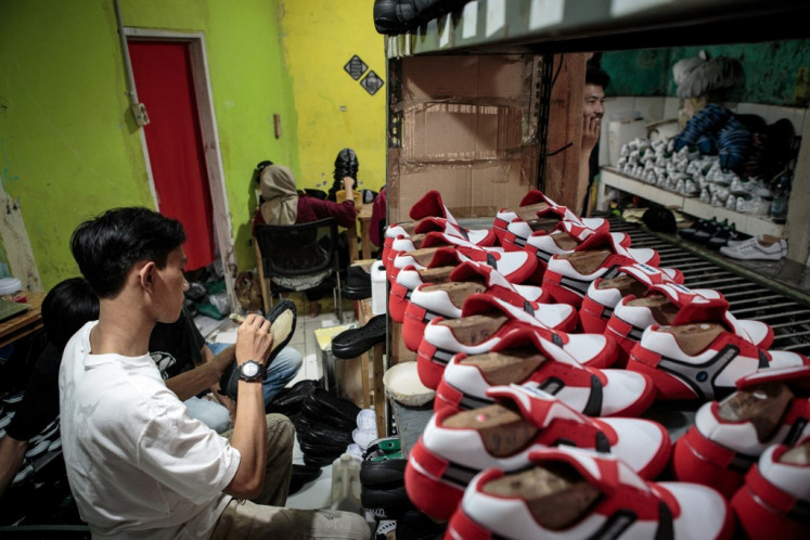A staff of a small shoe manufacturer makes their new products as they make an introductory video to be posted on social media in Bogor, West Java, on September 27, 2023.  