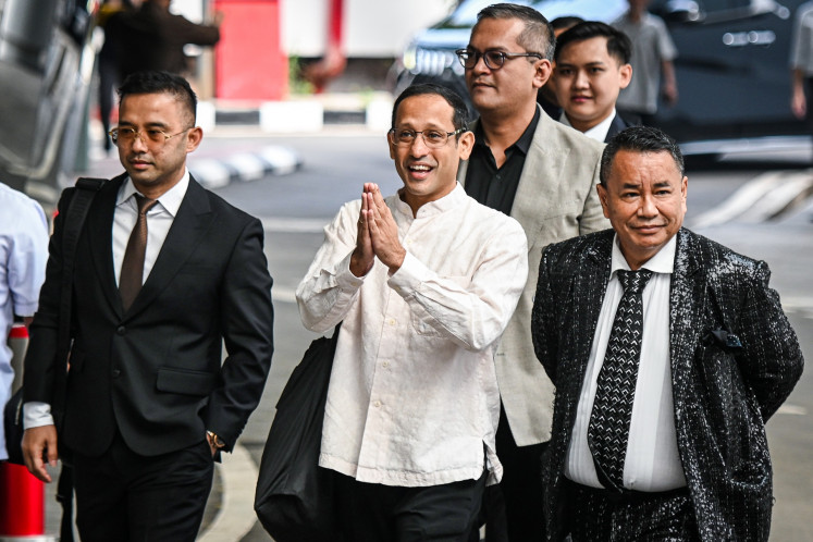 Former education, culture, research and technology minister Nadiem Makarim (center) walks with his lawyer Hotman Paris (right) upon arriving for an interrogation at the Attorney General's Office (AGO) headquarters in Jakarta on July 15, 2025. Investigators question the former minister as a witness in a corruption case pertaining to the procurement of Chromebook laptops in the then-education ministry.