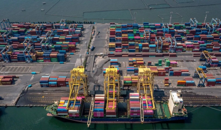 Export oriented: Using a rubber-tired gantry crane, port workers load export-bound containers onto a vessel carrying Portuguese flag at Tanjung Mas port in Semarang on June 24, 2025. 