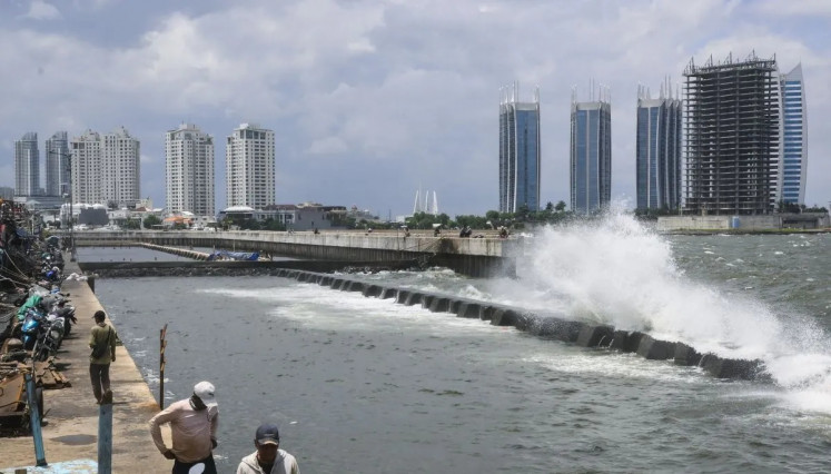 Sea defense: People walk near the sea wall built along Muara Baru port in North Jakarta on Feb. 5, 2025.