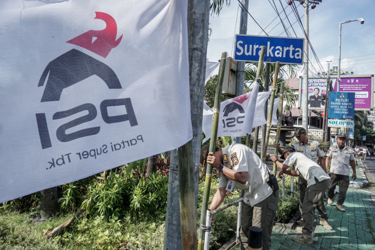 Surakarta Public Order Agency (Satpol PP) officers take down flags featuring the new logo of the Indonesian Solidarity Party (PSI) on July 16 in Surakarta, Central Java. The flags were installed in areas where banners featuring political party or mass organization emblems are prohibited as mandated by a 2023 mayoral regulation.