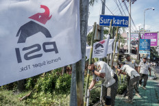 Surakarta Public Order Agency (Satpol PP) officers take down flags featuring the new logo of the Indonesian Solidarity Party (PSI) on July 16, 2025, in Surakarta, Central Java. The flags were installed in areas where banners featuring political parties and mass organizations are prohibited as mandated by a 2023 mayoral regulation.