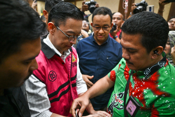 A guard puts a handcuff on former trade minister and graft convict Thomas Lembong (second left), who is accompanied by former Jakarta governor Anies Baswedan (third left) after the verdict hearing against him at the Jakarta Corruption Court in Jakarta on July 18. A panel of judges sentence Lembong to four-and-a-half years in prison and a Rp 750 million (US$45,871) fine after finding him guilty in a corruption case pertaining to the import of raw sugar.