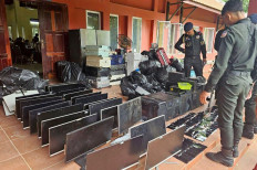 This photo taken on July 17, 2025 and released on July 18 by Agence Kampuchea Presse (AKP) shows military police personnel looking at computers, smartphones and other equipment seized during a raid on a scam center in Kandal province, Cambodia. The number of suspects arrested in a Cambodian crackdown on internet scam centers has risen to 2,000, a government minister told AFP on July 18.