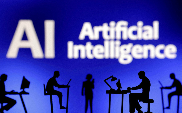 Figures with computers and smartphones are seen in front of the words “Artificial Intelligence“ in this illustration created on Feb. 19, 2024.