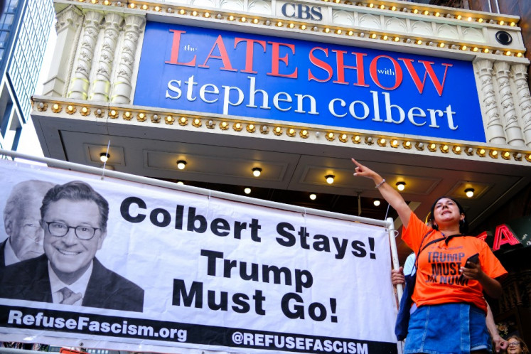 People participate in a protest titled 'Colbert stays! Trump must go!' outside the Ed Sullivan Theater in New York City on July 21, 2025. “The Late Show with Stephen Colbert,“ a staple of late-night US television, will end in 2026, the CBS network said, days after the comedian blasted parent company Paramount's $16 million settlement with President Donald Trump as “a big fat bribe.“