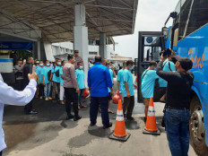A group of migrant workers (in light blue shirts) board a bus on July 21, 2025, after arriving at Batam Center Port in Batam, the Riau Islands, as part of the 232 Indonesian migrant workers who were repatriated through a program coordinated between the Malaysian Immigration Department and the Indonesian Consulate General in Johor Bahru, Johor state.