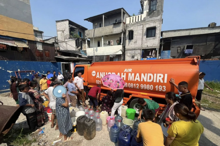 People in Kapuk Muara subdistrict in Penjaringan, North Jakarta, line up with buckets to collect clean water on July 20 from a water truck they rented through pooled funds. 