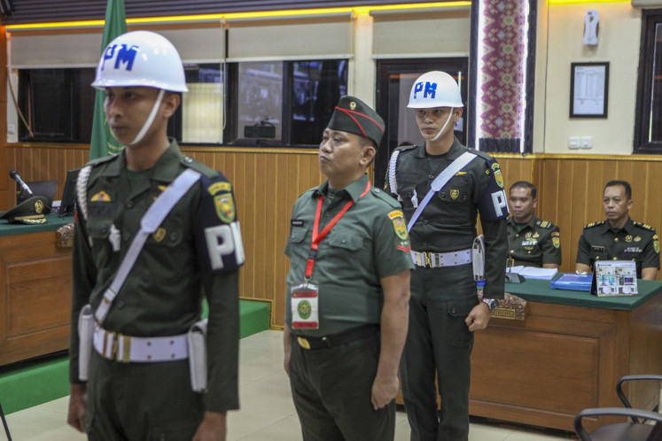 Defendant Second Cpl. Bazarsah (center) is flanked by two Military Police officers during his murder trial at the Palembang Military Court in Palembang on July 21. Military prosecutors demanded the death penalty for Bazarsah for allegedly killing three policemen during a raid on his gambling den.