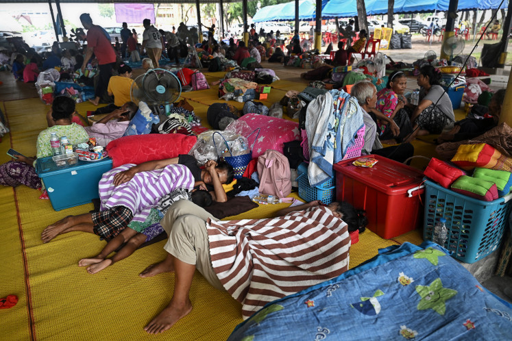 Evacuees displaced by the ongoing conflict between Thailand and Cambodia rest at a makeshift evacuation center inside a Buddhist temple in the Thai border province of Si Sa Ket on July 26, 2025. The death toll in Cambodia from clashes with Thailand has risen to 13, Phnom Penh's defense ministry said July 26, with more than 35,000 people forced to flee their homes.