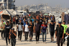 Humanitarian pause: Palestinians gather on Sunday as they wait for aid supplies to enter Gaza, in the northern Gaza Strip.