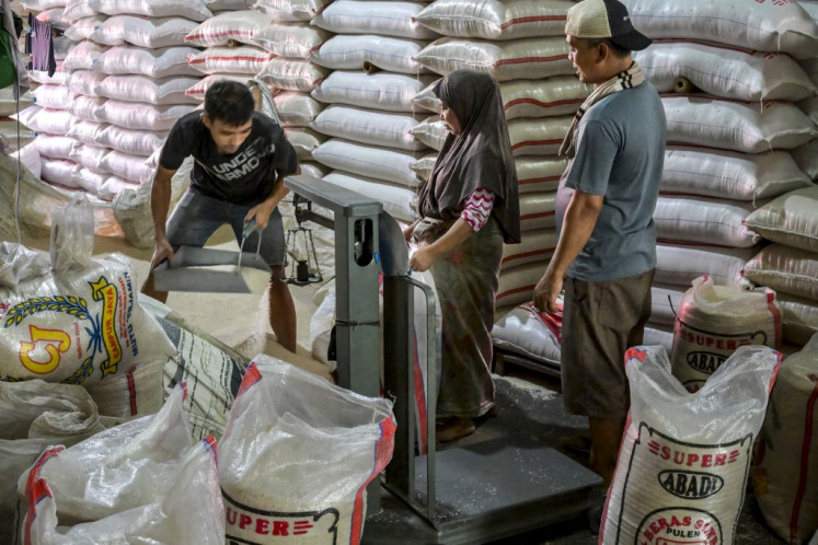 A worker weighs rice on July 9, 2025, as he serves a customer at a rice market in Jakarta.