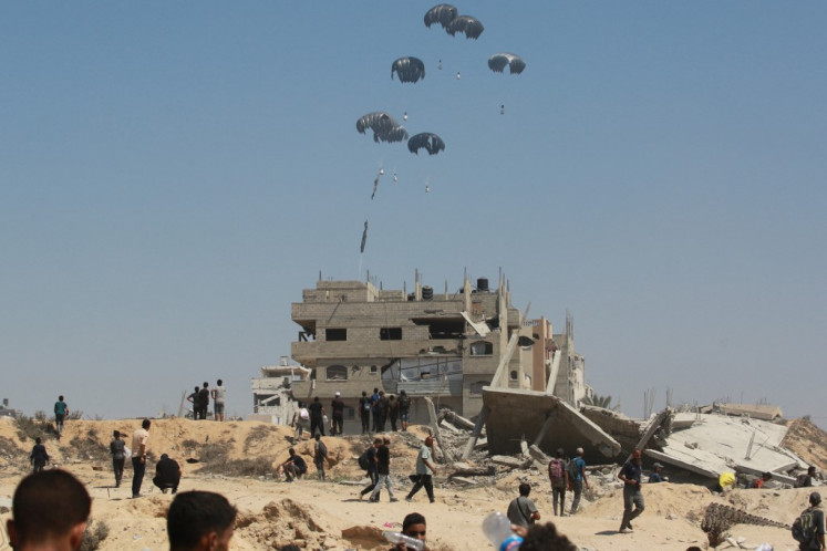 A military transport aircraft drops humanitarian aid over the northern Gaza Strip, on July 27, 2025. Jordanian and Emirati planes dropped food into Gaza on July 27, as Israel began a limited “tactical pause“ in military operations to allow the UN and aid agencies to tackle a deepening hunger crisis. 