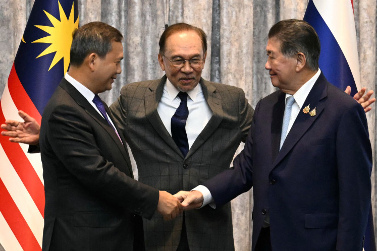 Cambodia's Prime Minister Hun Manet (left) and Thailand's acting Prime Minister Phumtham Wechayachai (right) shake hands as Malaysia's Prime Minister Anwar Ibrahim puts his arms around them following a press conference after talks on a possible ceasefire between Thailand and Cambodia in Putrajaya on July 28, 2025. Thailand and Cambodia began discussing a ceasefire in their festering border dispute on July 28, as the deadly skirmish dragged into a fifth day.