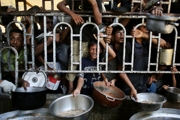 Palestinian children wait for a meal at a charity kitchen in the Mawasi area of Khan Yunis in the southern Gaza Strip on July 22, 2025.