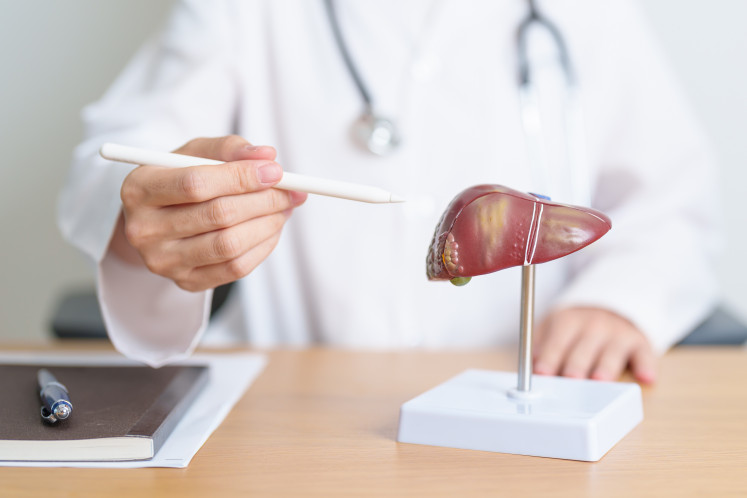 Illustration of a doctor showing a human liver anatomy model.