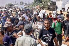 Palestinians carry personal belongings as they walk in the Mawasi area of Rafah in the southern Gaza Strip on July 28, 2025. 