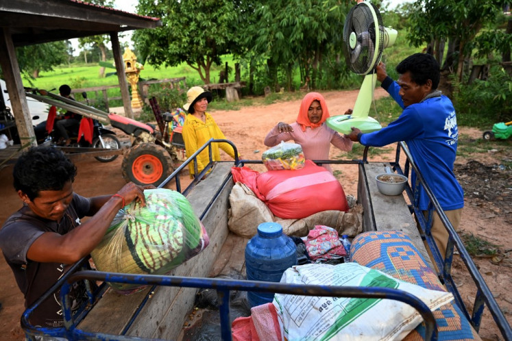 Lat Laem, a displaced Cambodian farmer (left) carries his belongings upon returning home in Kouk Khpos village, Oddar Meanchey province on July 29, 2025, after Thailand truce. As Cambodia and Thailand's ceasefire held on July 29, Lat Laem hared back home -- one of the first evacuees to return to the frontier since deadly cross-border clashes sent more than 300,000 people fleeing. 