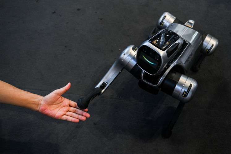 A man interacts with a quadruped robot named “Magic Dog“ by Magiclab on July 29 during the World Artificial Intelligence Conference (WAIC) at the Shanghai World Expo and Convention Center in Shanghai.